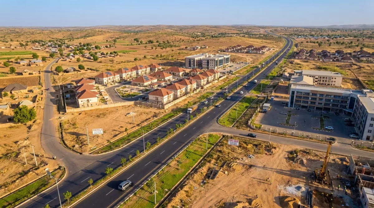 Aerial view of a modern highway corridor in Gombe State, Nigeria, featuring residential estates, commercial buildings, undeveloped land parcels, and ongoing construction, illustrating the region's growing real estate and infrastructure development.