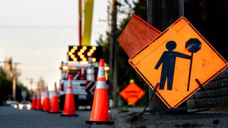 Road construction warning sign and orange traffic cones positioned along a roadway during a temporary traffic diversion, highlighting ongoing infrastructure and drainage upgrade works.