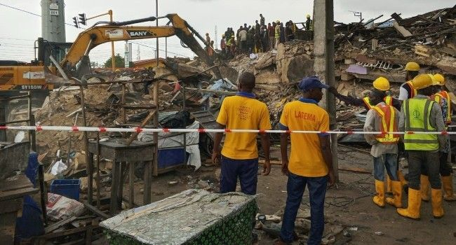 Emergency responders, construction workers, and heavy equipment clear the rubble of a collapsed building in Lagos as officials inspect the disaster scene and begin rescue operations.